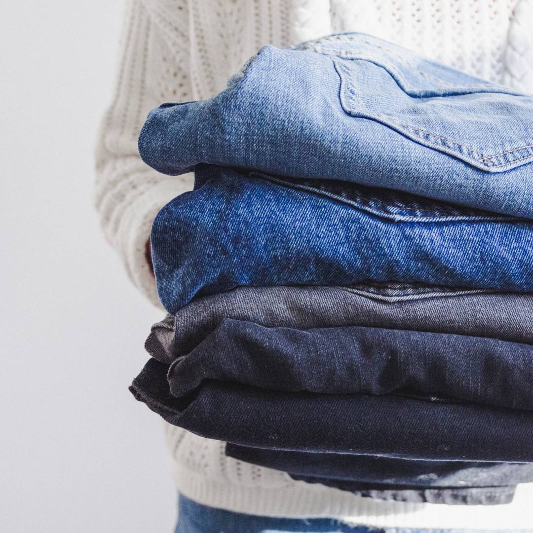 Person Holding A Pile Of Jeans